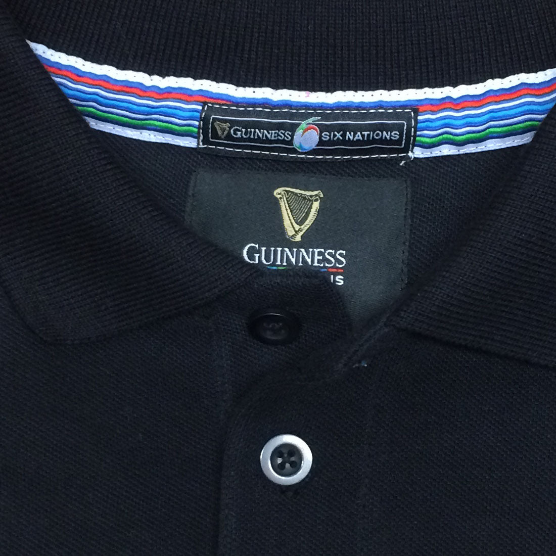Six Nations Black Polo Shirt with a striped collar detail, featuring a Guinness Six Nations label above and a Guinness brand logo embroidered below the collar, perfect for any rugby fan.