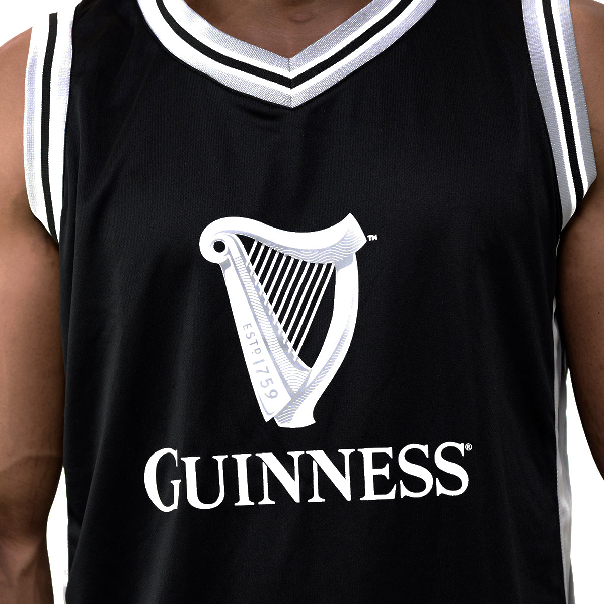A soccer fan proudly sports a Guinness Black & Grey Basketball Jersey from Guinness Webstore US, featuring the iconic harp logo and "ESTD 1759," blending classic style with sporty passion seamlessly.