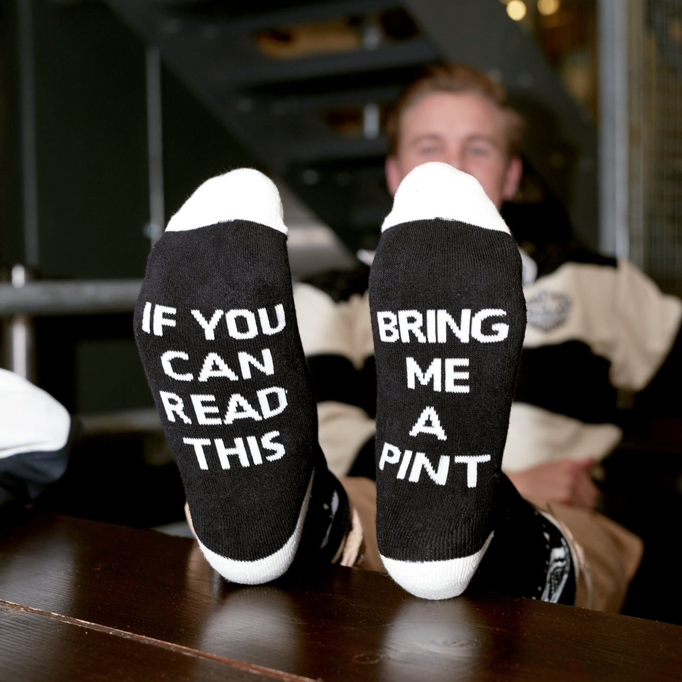 Relaxing with their feet up, someone proudly shows off their Guinness Harp 'Bring me a Pint' socks from Guinness, ideal for any fan of the iconic beverage.