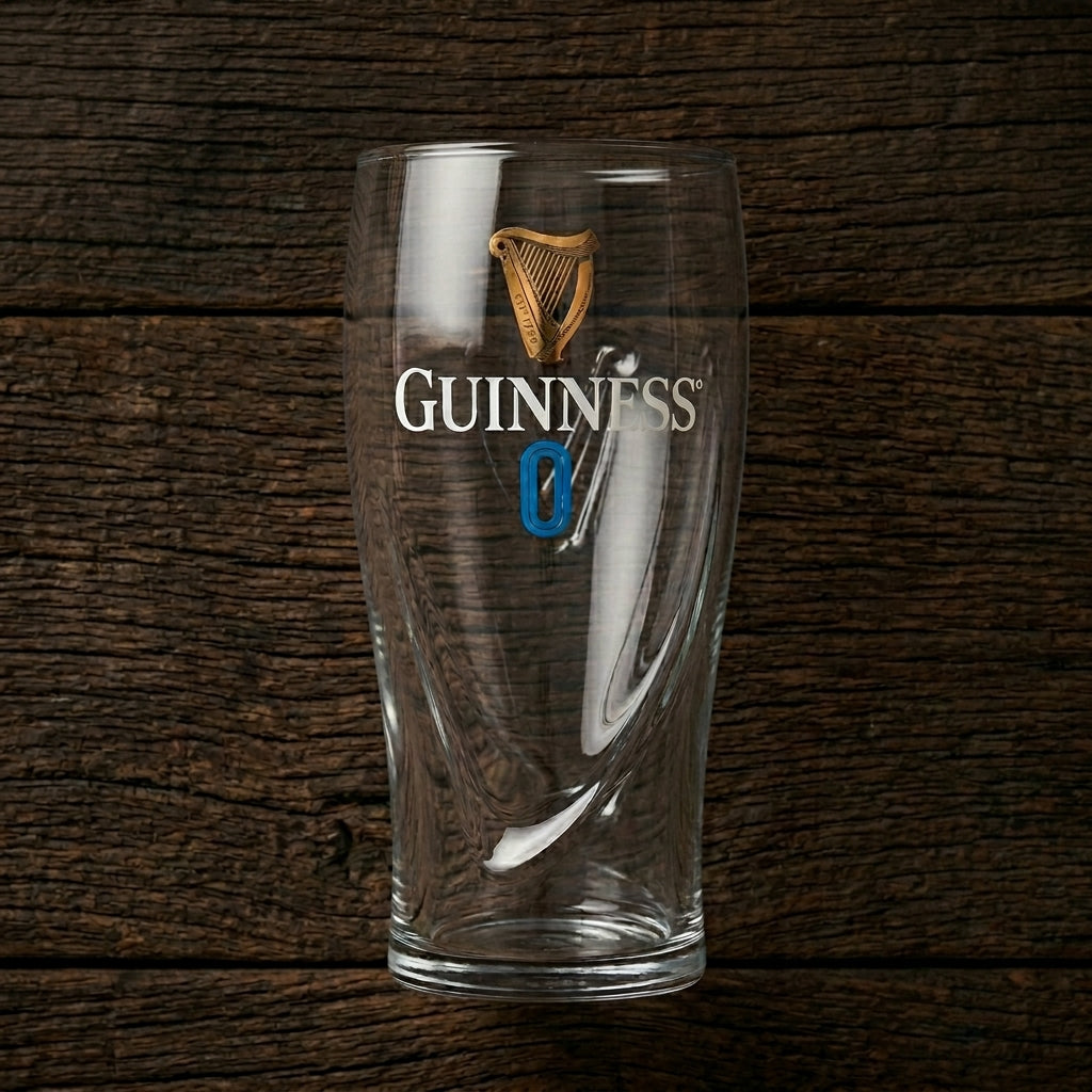 The Guinness 0 Gravity Pint Glass from Guinness Webstore US features the iconic logo and a bold blue zero, displayed against a dark wooden background.