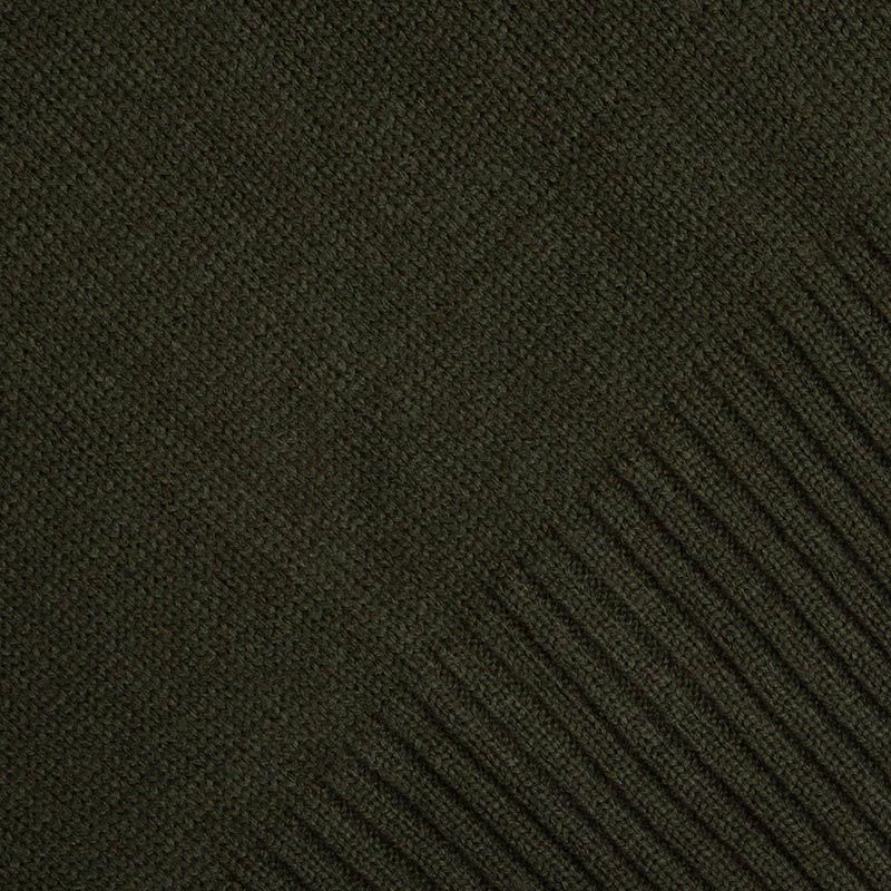 Close-up of the textured dark green knitted fabric of the Guinness Bottle Green Crew Neck Jumper, highlighting the iconic Evolution Harp subtly woven into the ribbed pattern along the right edge. Available at Guinness Webstore US.