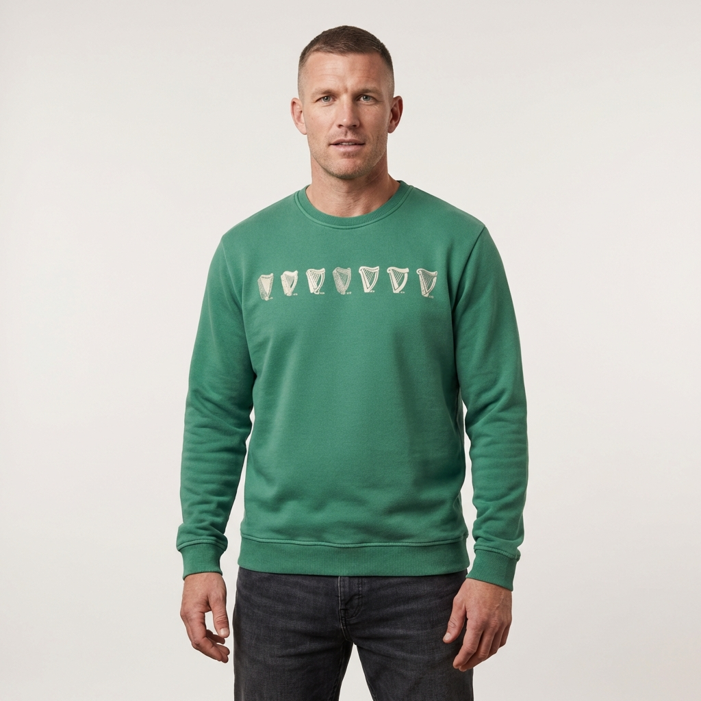 A man wears a Guinness Webstore US Evolution Harp Green Sweatshirt with stylized pint glass graphics across the chest, standing against a plain light background.