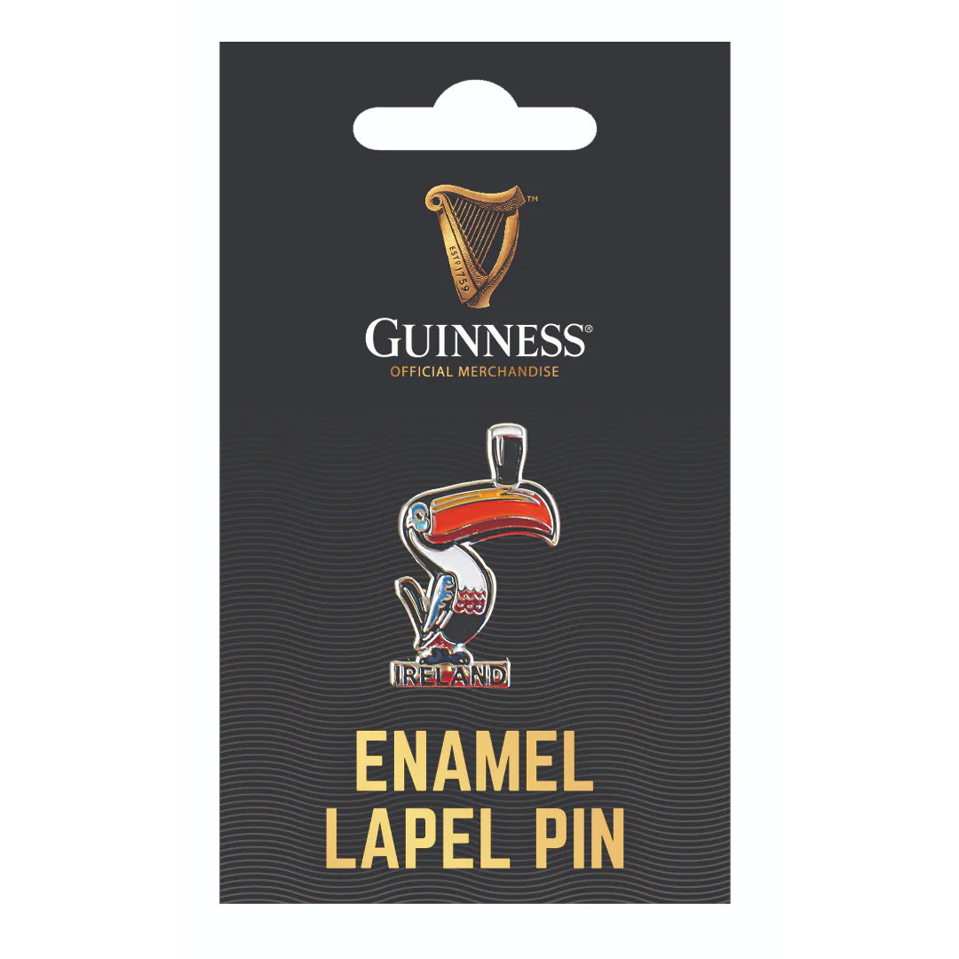 The Guinness Toucan Lapel Pin highlights a toucan balancing a pint glass and features the word "Ireland." Ideal for holiday decorations, it is presented on a black card with the famous Guinness logo.