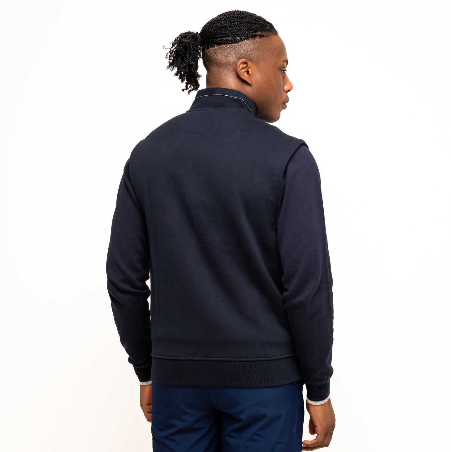 A person faces away from the camera against a white background, wearing the Guinness Performance Gilet from Guinness Webstore US, paired with navy shorts.