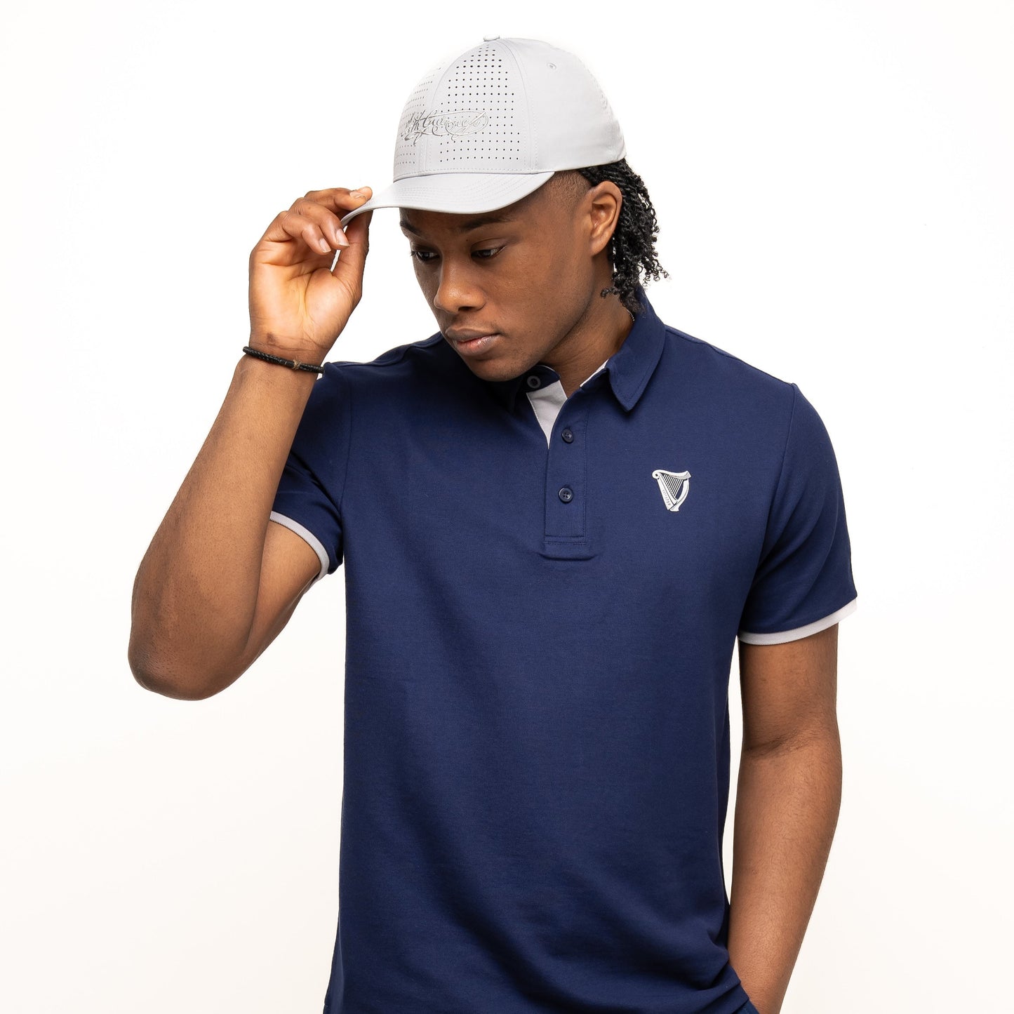 A man wearing the Guinness Performance Polo in navy from Guinness Webstore US and a white hat.