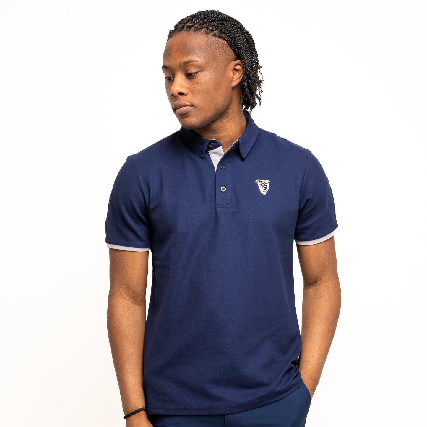 A person wears the Guinness Performance Polo - Navy from Guinness Webstore US, featuring breathable fabric and a small white chest emblem, standing against a plain white background.