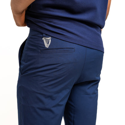A person is seen from behind wearing Guinness Performance Shorts - Navy from Guinness Webstore US, featuring a harp logo above the back pocket. Made of moisture-wicking fabric, these shorts are paired with a matching shirt.