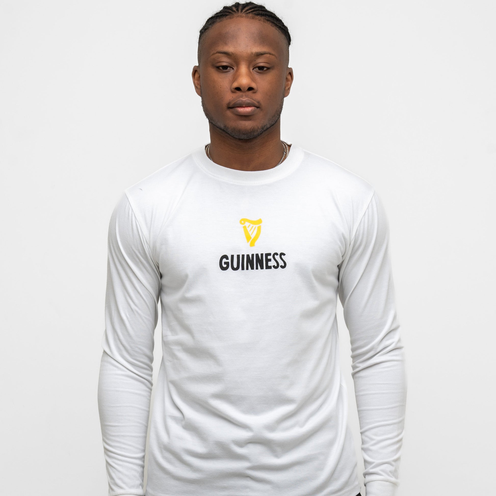 A person faces forward in the Guinness Seb Curi Lovely Day Longsleeve Tee - White from Guinness Webstore US, featuring the brand’s iconic logo and text on the front, against a plain white background.