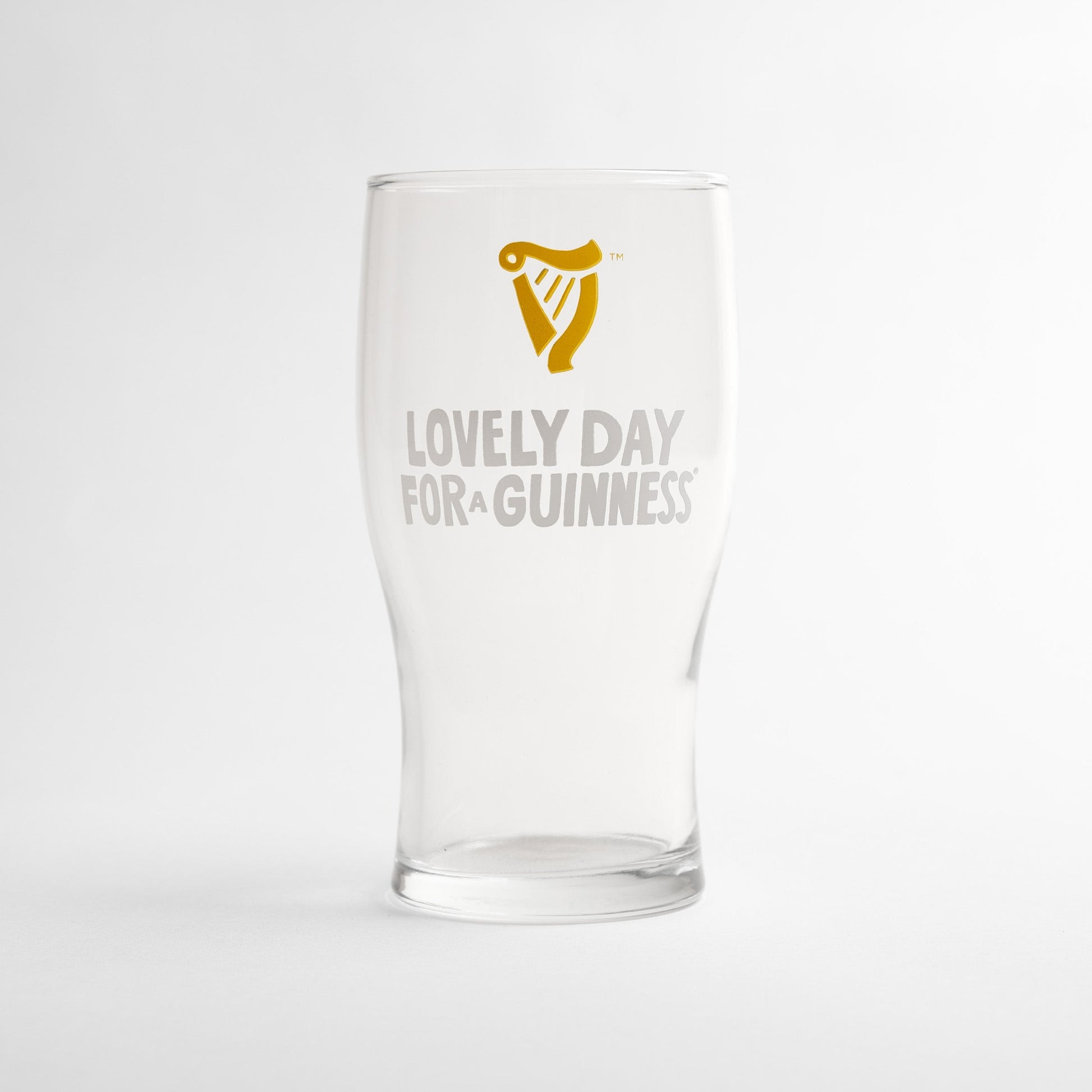 The Guinness Seb Curi Lovely Day Pint Glass from Guinness Webstore US is a collector’s edition pint glass featuring the iconic harp logo and "Lovely Day for a Guinness" on the front.