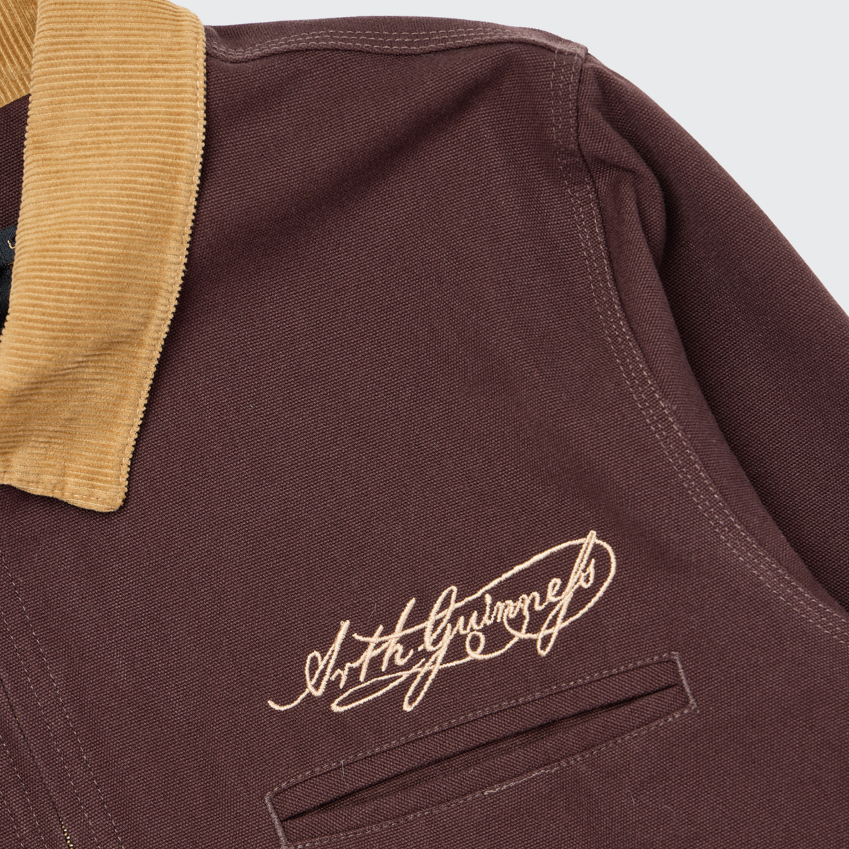 The Guinness Cooperage Work Jacket is maroon heavyweight cotton canvas with a tan corduroy collar and embroidered signature above the chest pocket.