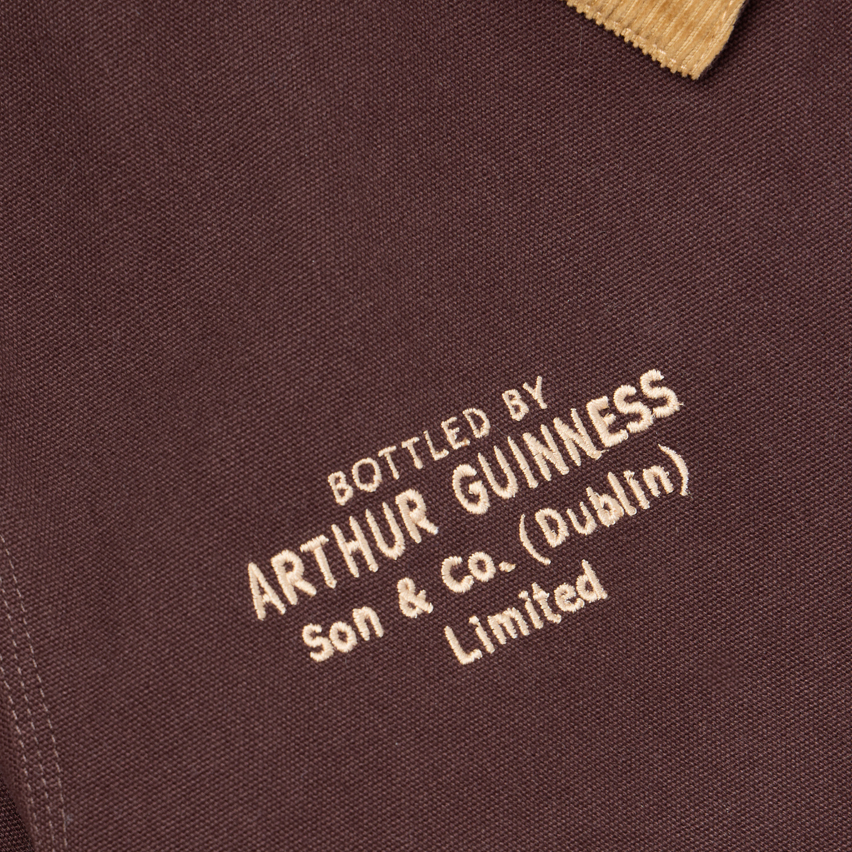 The Guinness Cooperage Work Jacket features heavyweight brown cotton canvas and beige “Bottled by Arthur Guinness Son & Co. (Dublin) Limited” embroidery under a corduroy collar.