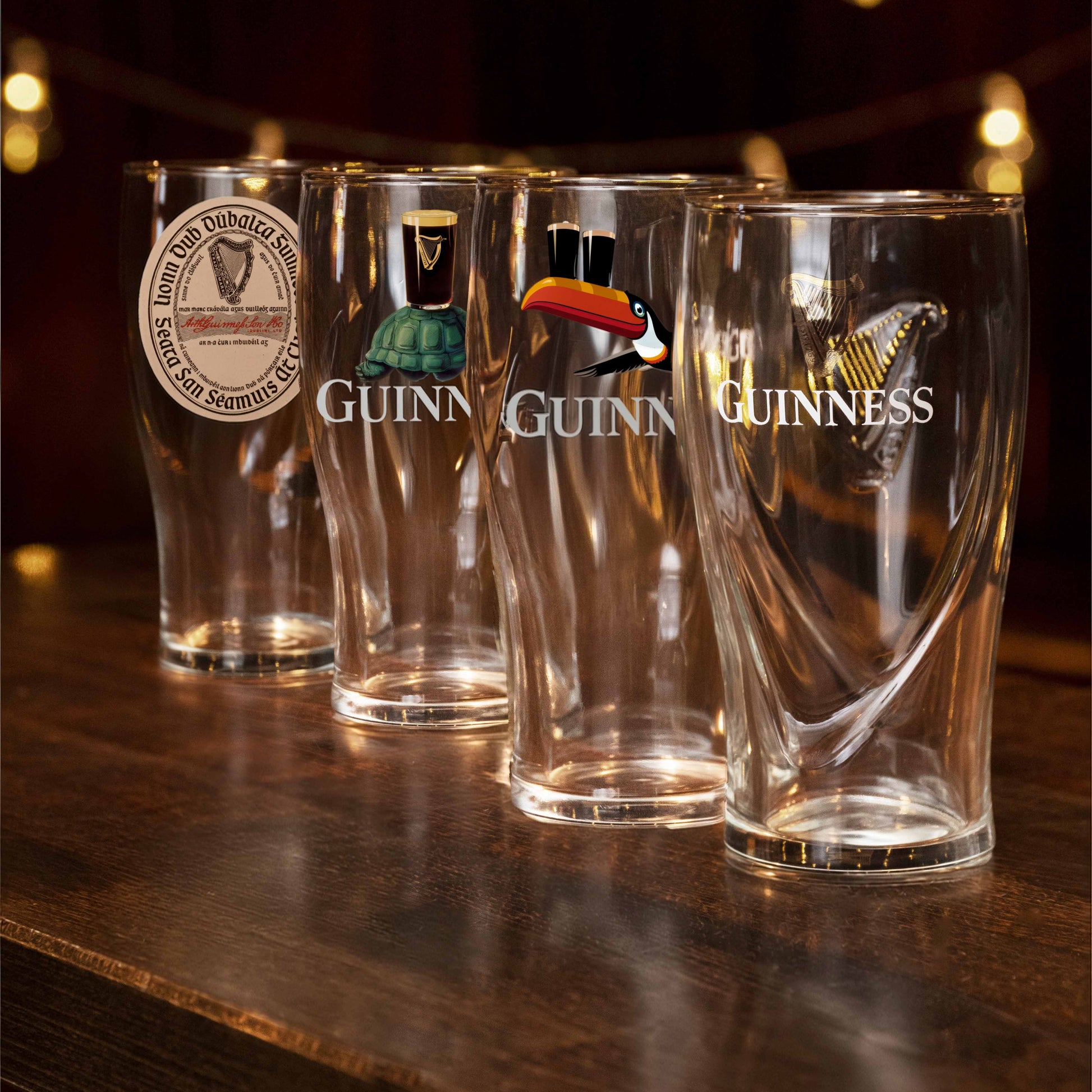 Four Guinness glasses on a wooden surface with a dark background
