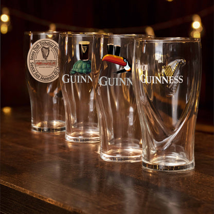 Four Guinness glasses on a wooden surface with a dark background
