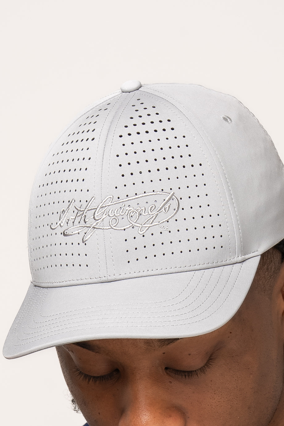 A person wearing the Guinness Performance Signature Cap from Guinness Webstore US, featuring embroidered cursive text and quick-dry technology, shown from the nose up.