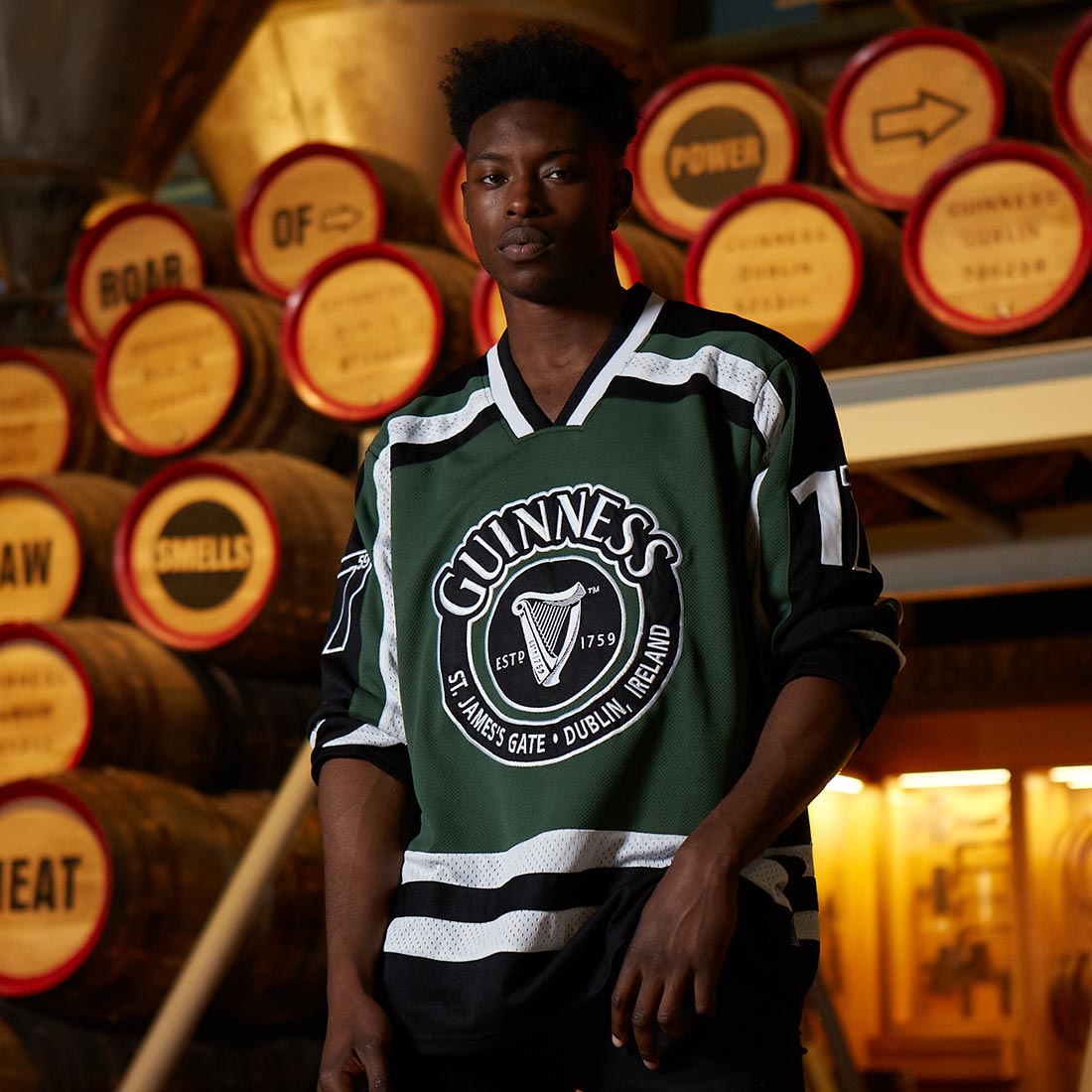 A young man wearing a green and black Guinness hockey jersey made of polyester.
