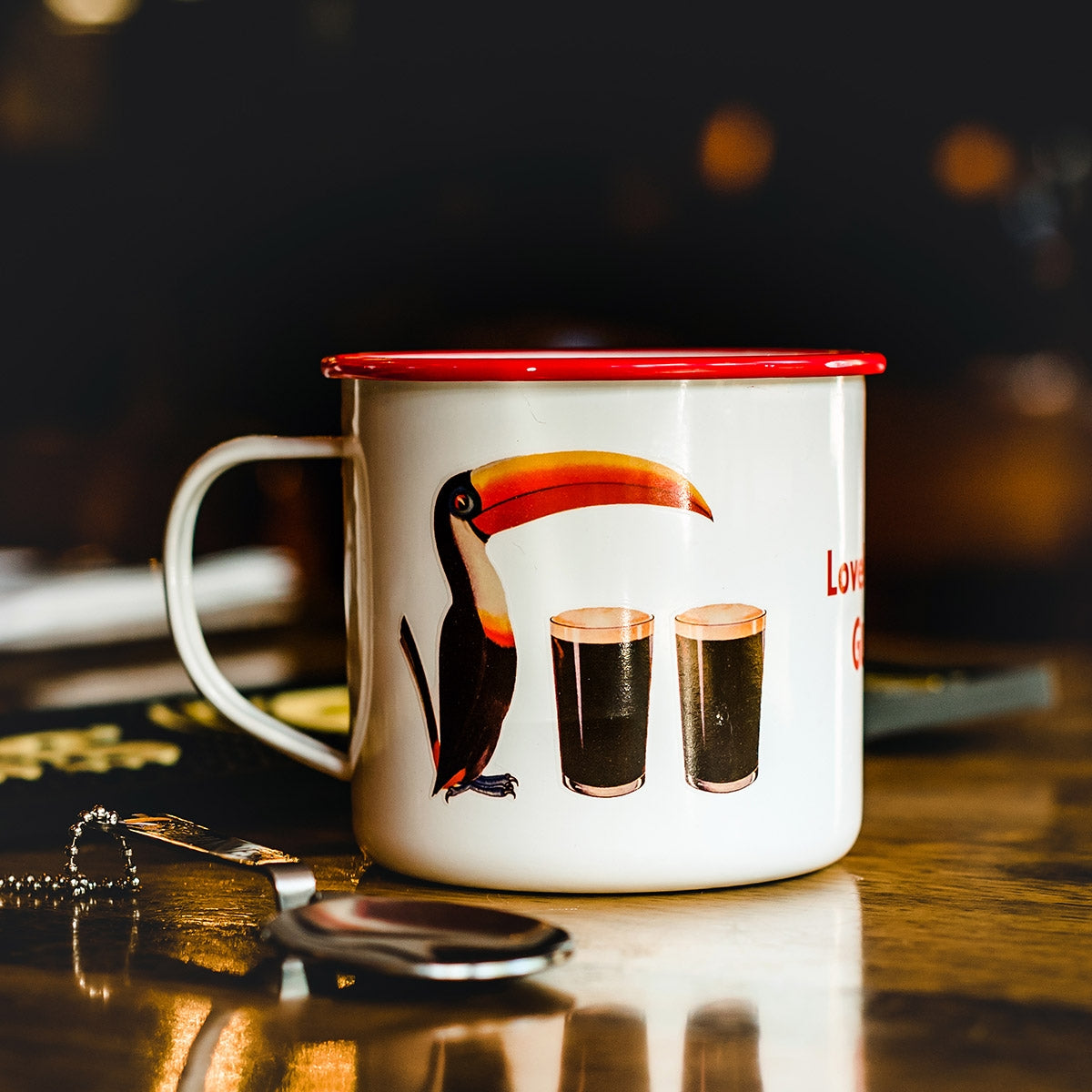 A Guinness enamel toucan mug sits on a table.