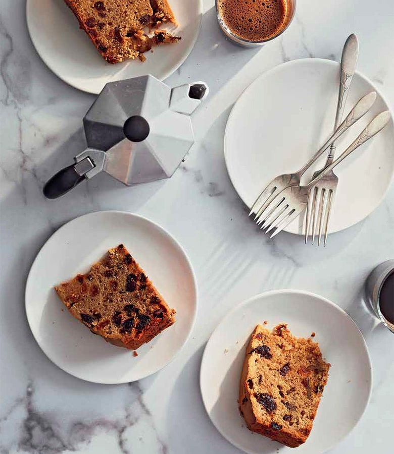 A slice of Official Guinness Hardcover Cookbook bread on a plate next to a cup of coffee.