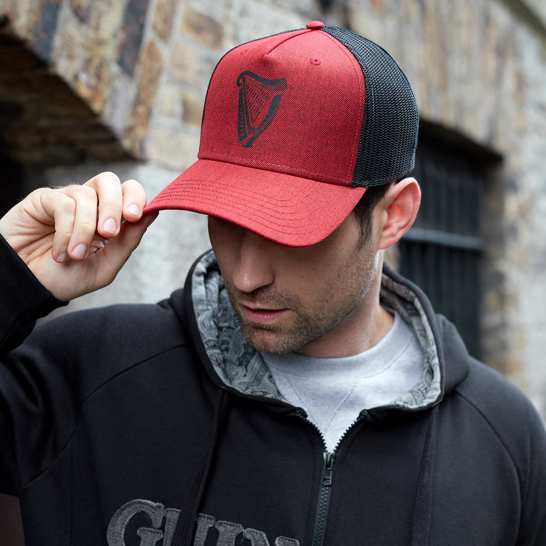 A Guinness Trucker Premium Black & Red Harp Cap-wearing man.