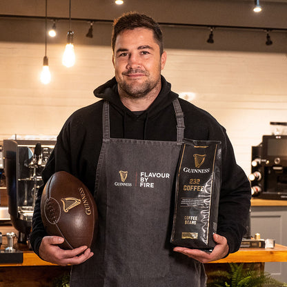 A man in an apron holding a limited-edition bag of Guinness Ground Coffee 227g.
