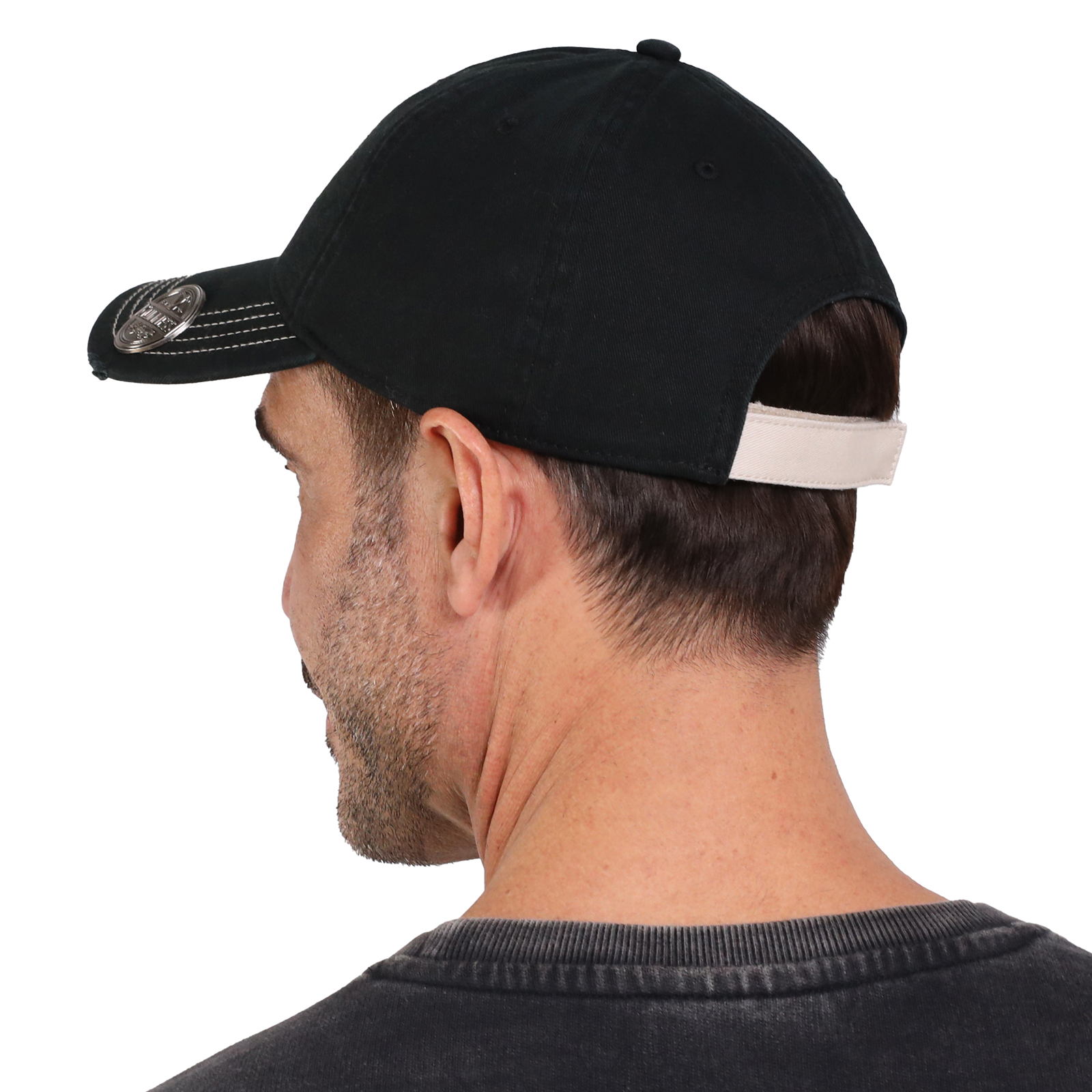 The man is wearing an official Guinness merchandise Gaelic Bottle Opener Cap and a gray T-shirt, viewed from the back.