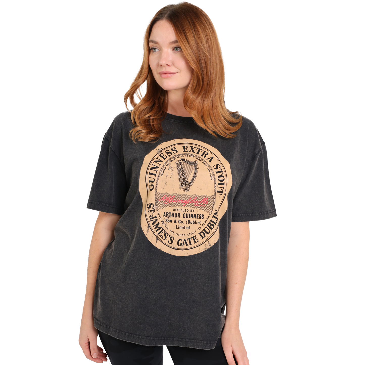 A person with long hair is seen wearing a black, oversized Guinness Black Distressed Label Tee against a white background. The shirt proudly displays the Arthur Guinness signature print and is crafted from 100% cotton.