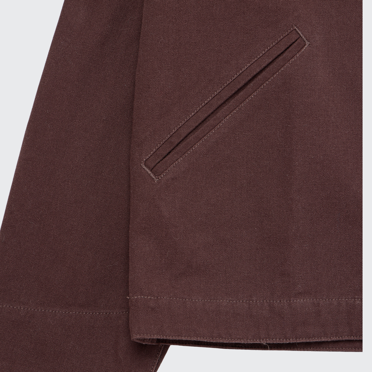 Close-up of the Guinness Cooperage Work Jacket by Guinness Webstore US, featuring a diagonal slit pocket and visible stitching on heavyweight cotton canvas near the hem and sleeve.