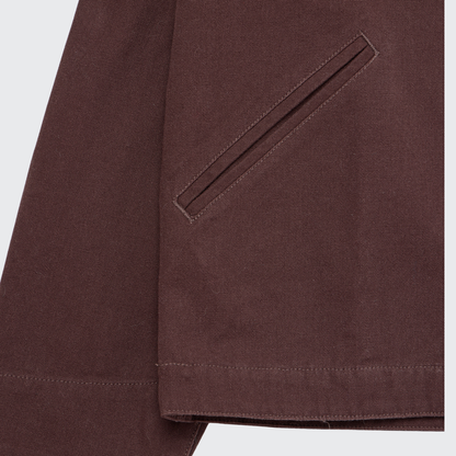 Close-up of the Guinness Cooperage Work Jacket by Guinness Webstore US, featuring a diagonal slit pocket and visible stitching on heavyweight cotton canvas near the hem and sleeve.