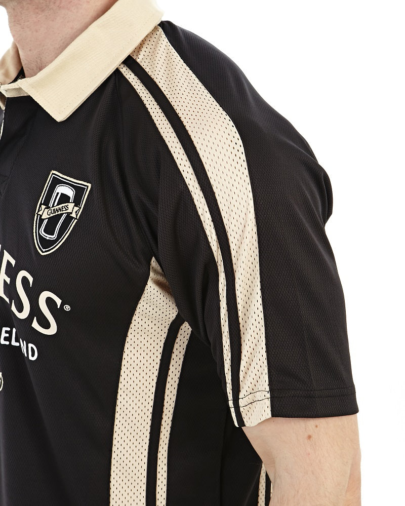 A man wearing a black and beige Guinness PERFORMANCE RUGBY JERSEY.