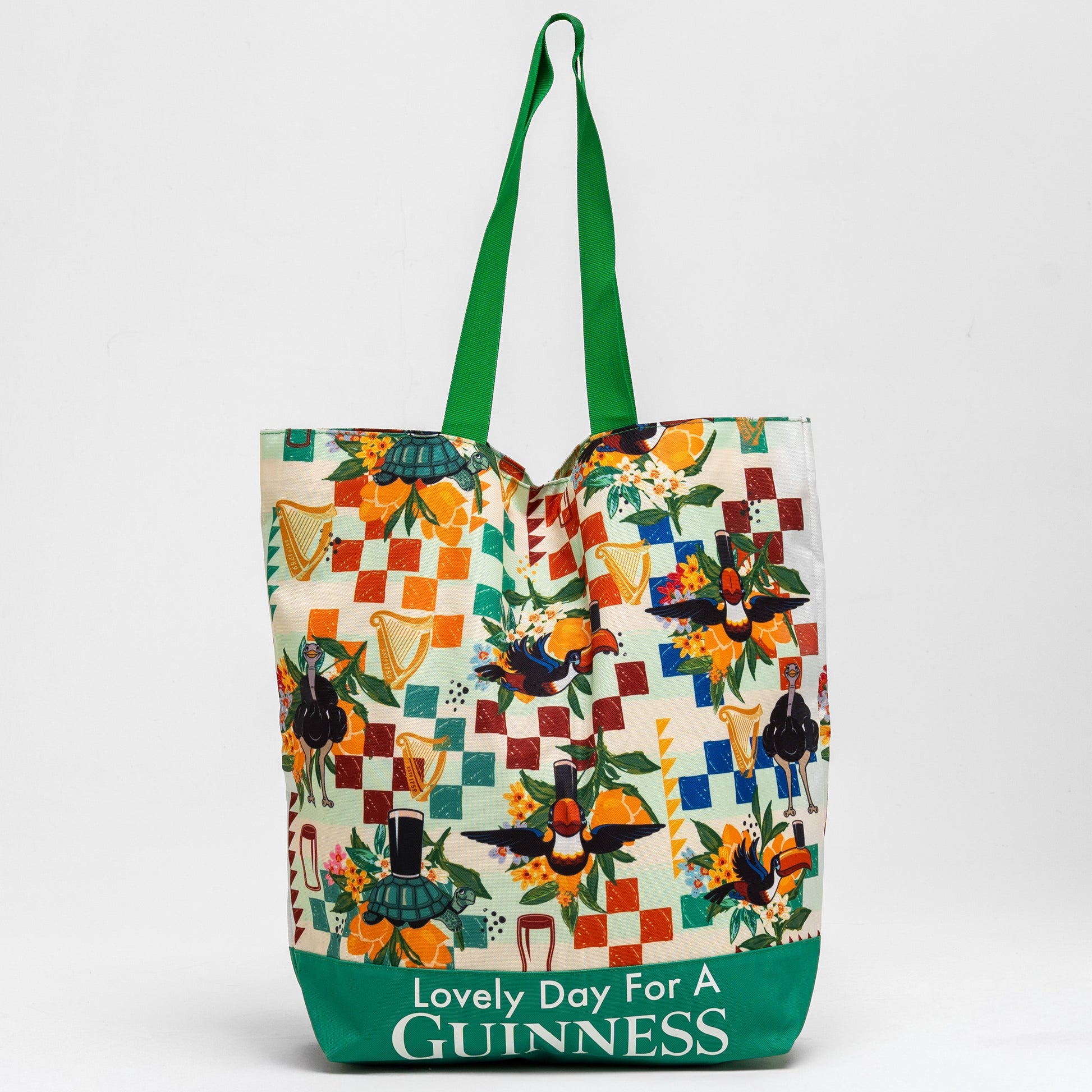 The Guinness Toucan Beach Bag from Guinness Webstore US features a vibrant patchwork of birds and harps, green handles, and "Lovely Day For A Guinness" text. With a spacious 20L capacity, it's perfect for carrying all your essentials.
