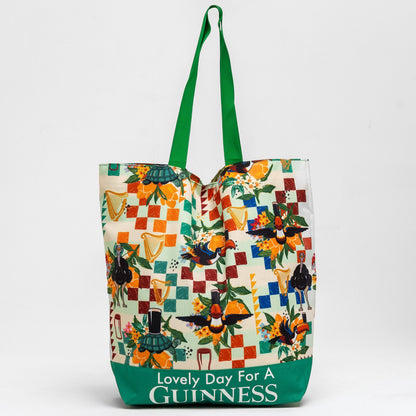 The Guinness Toucan Beach Bag from Guinness Webstore US features a vibrant patchwork of birds and harps, green handles, and "Lovely Day For A Guinness" text. With a spacious 20L capacity, it's perfect for carrying all your essentials.