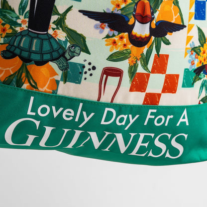 A vibrant illustration featuring a toucan, turtle, flowers, and "Lovely Day For A Guinness" text on green, inspired by Hawaiian patterns. Ideal for fans of the spacious 20L Guinness Toucan Beach Bag from Guinness Webstore US.