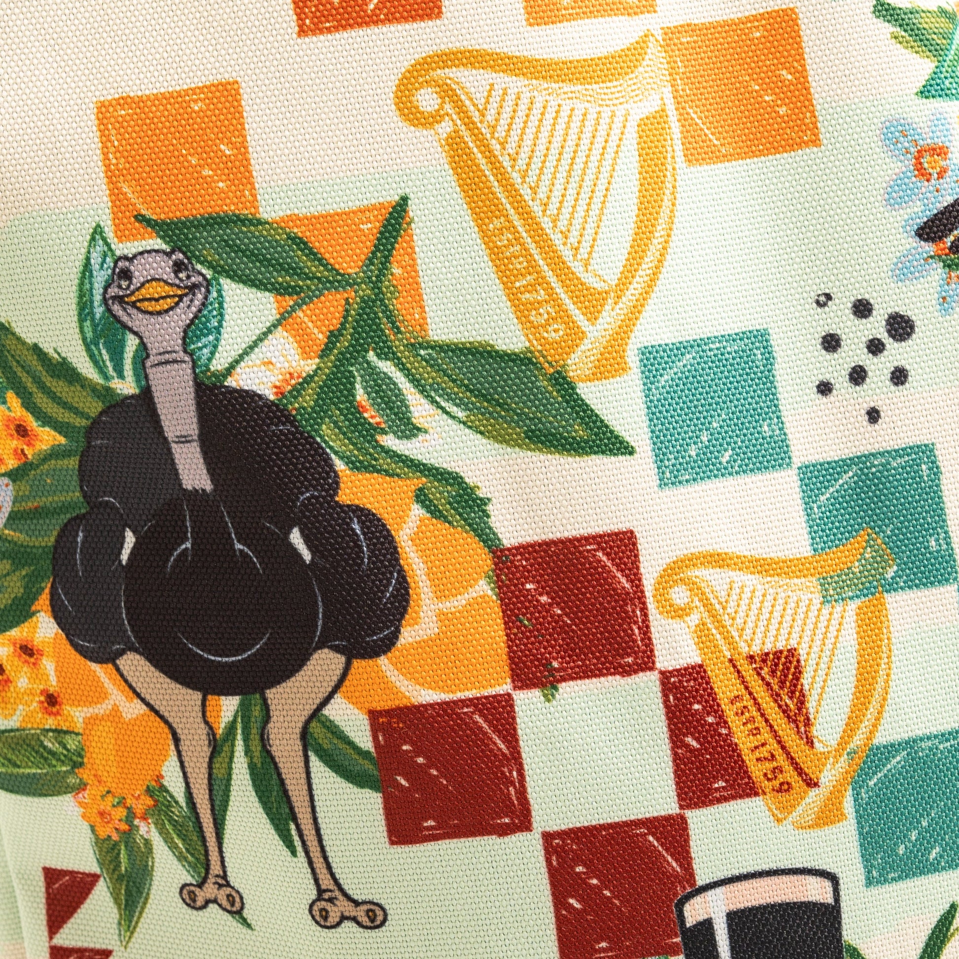 The Guinness Toucan Beach Bag from Guinness Webstore US features a playful toucan with boxing gloves among checkerboard patterns, yellow harps, flowers, and a black hat on fabric inspired by vibrant Hawaiian designs.