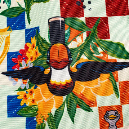 The Guinness Webstore US Guinness Toucan Beach Bag features a bold Hawaiian print with a toucan, yellow flowers, and green leaves on a red and blue checkerboard background. This vibrant 20L bag is perfect for your next beach outing.