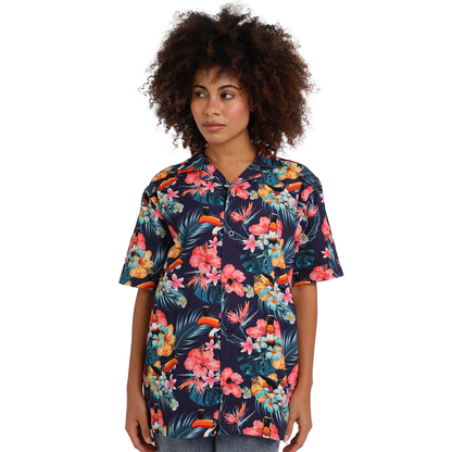 A person with curly hair is wearing a dark short-sleeved shirt featuring a vibrant tropical floral design, reminiscent of a classic Guinness Toucan Hawaiian Shirt by Guinness.