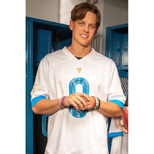 A young man in a Guinness 0 Football Jersey - White from Guinness Webstore US is standing next to a locker.