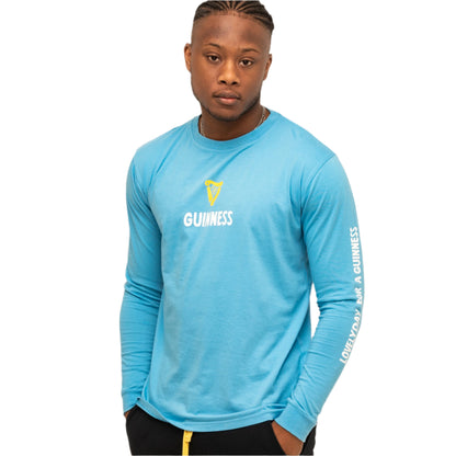 A man wears the blue Guinness Seb Curi Lovely Day Longsleeve Tee from Guinness Webstore US with white text, standing against a plain white background.