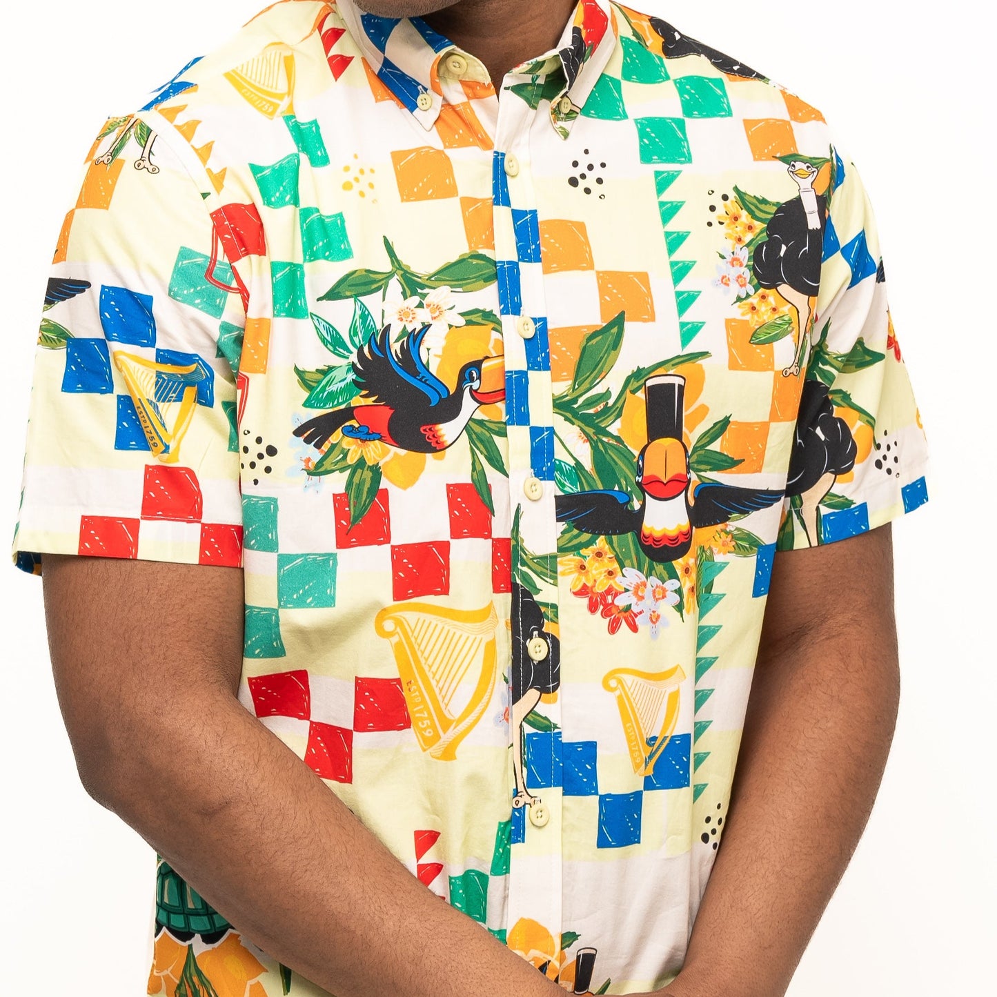 A person wearing the Guinness Toucan Beach Shirt from Guinness Webstore US, featuring vibrant toucans, harps, and leaves in classic Hawaiian style on breathable cotton.