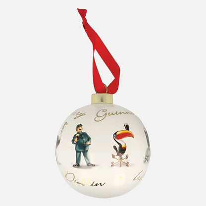 The Guinness Gilroy Ceramic Holiday Bauble features a white finish, red ribbon, and illustrations of a man and toucan with gold text—an ideal festive decoration from the iconic Guinness brand.
