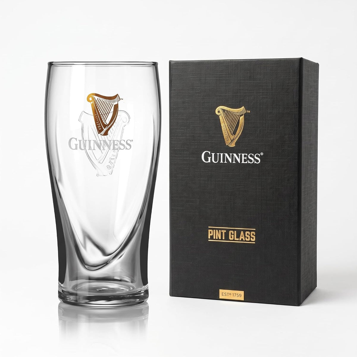 A Guinness® Pint Glass with Gift Box featuring a golden harp logo next to its black rectangular gift box.