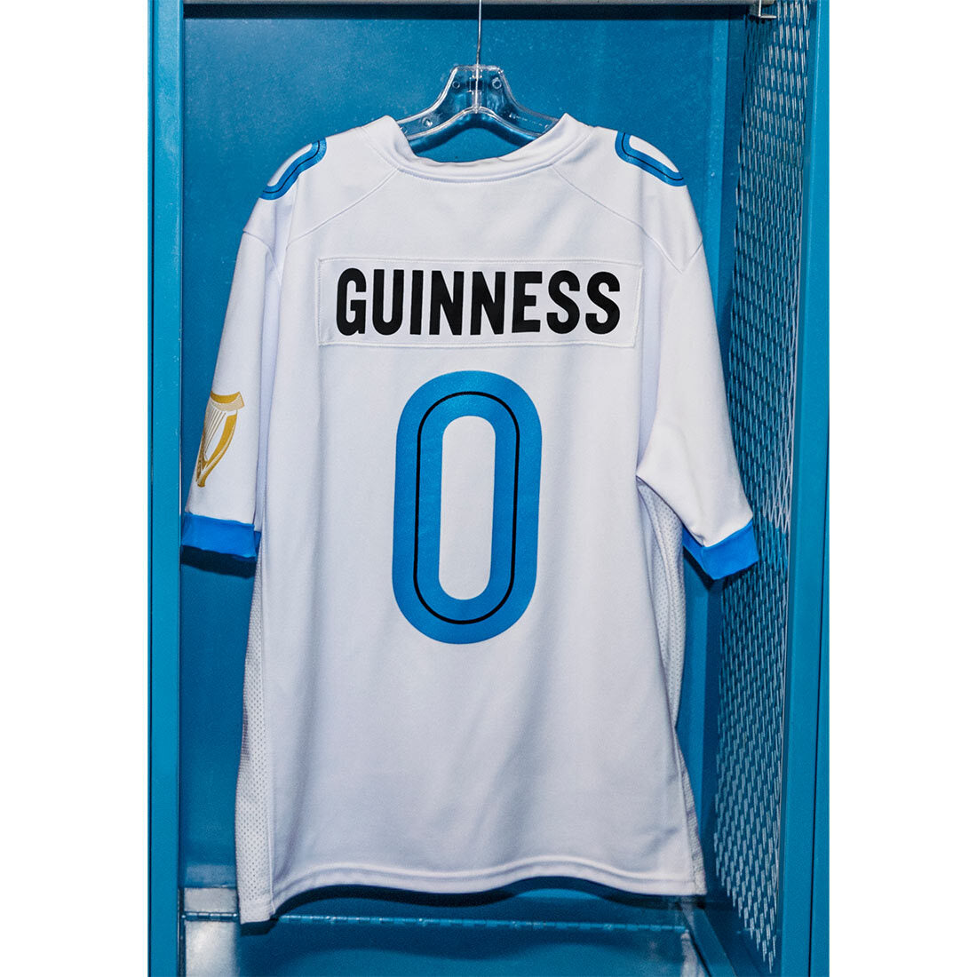 A Guinness Webstore US white football jersey with the number 0 hanging in a locker.