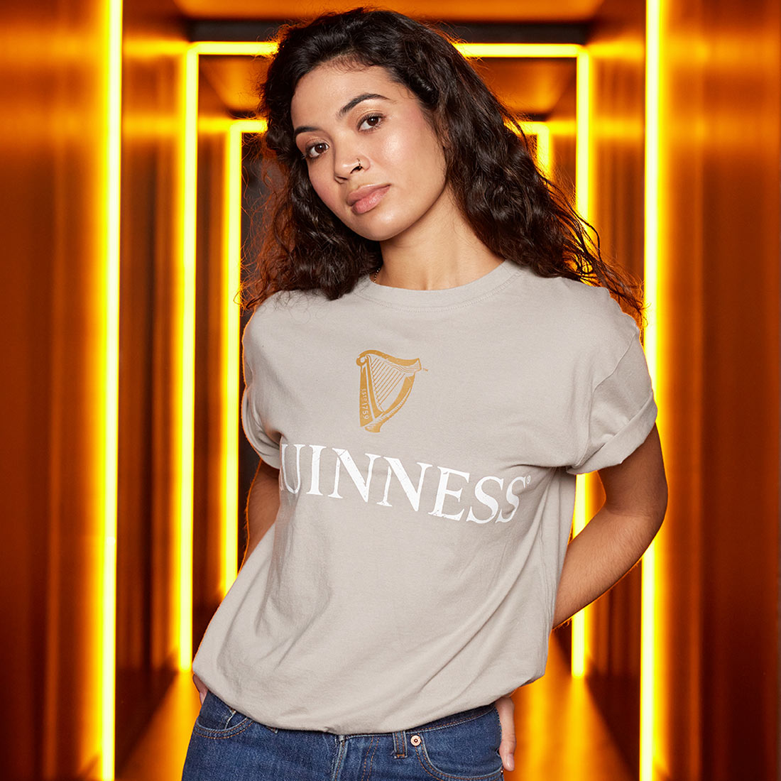 A woman wearing a cotton Guinness Trademark Label T-Shirt Beige in a hallway.