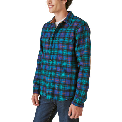 A man wearing a limited edition Guinness Webstore US Guinness Wool Plaid Over Shirt With Elbow Patch - Green Plaid.