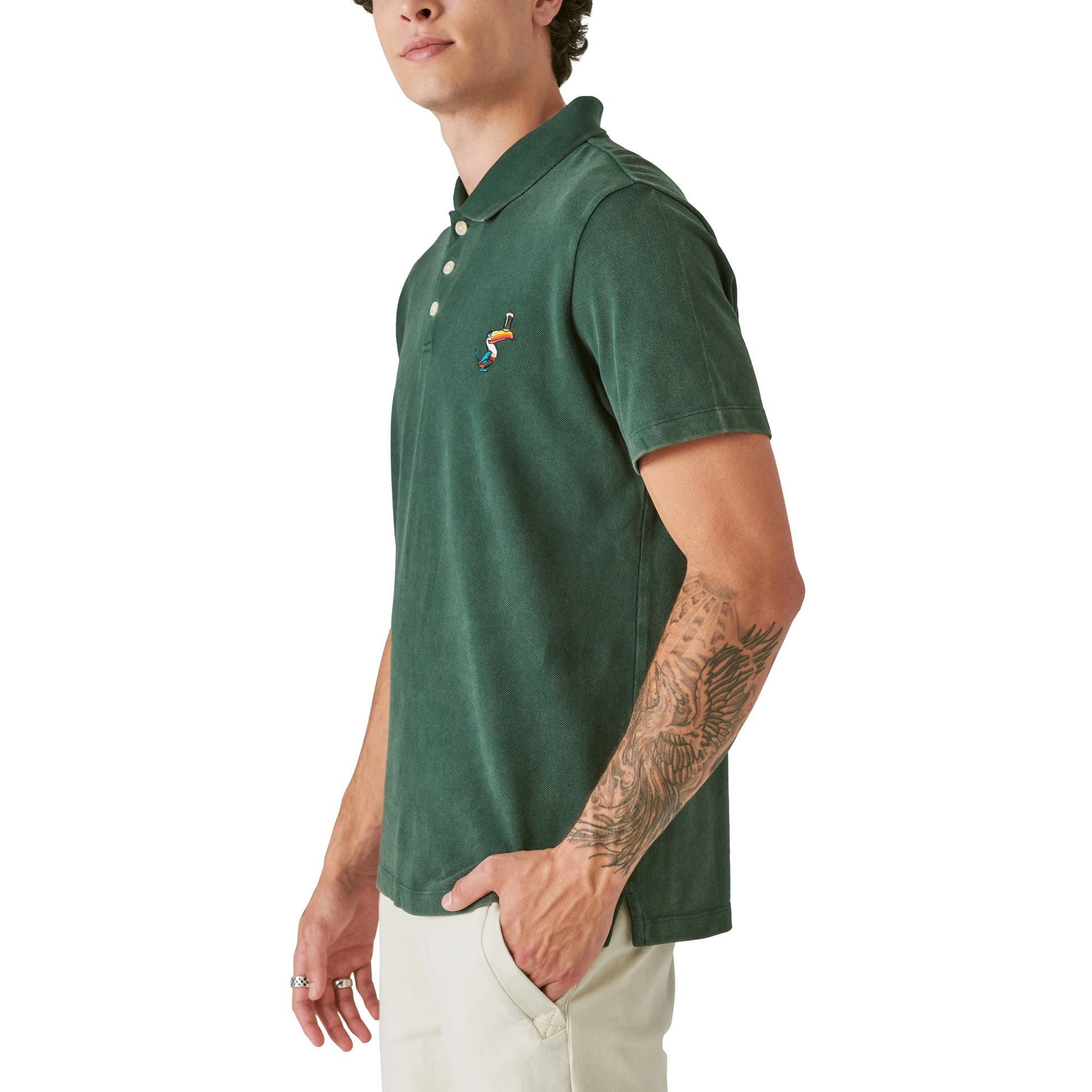 A man wearing a Guinness Polo - Pine Grove shirt in the color green and white pants from Guinness Webstore US.