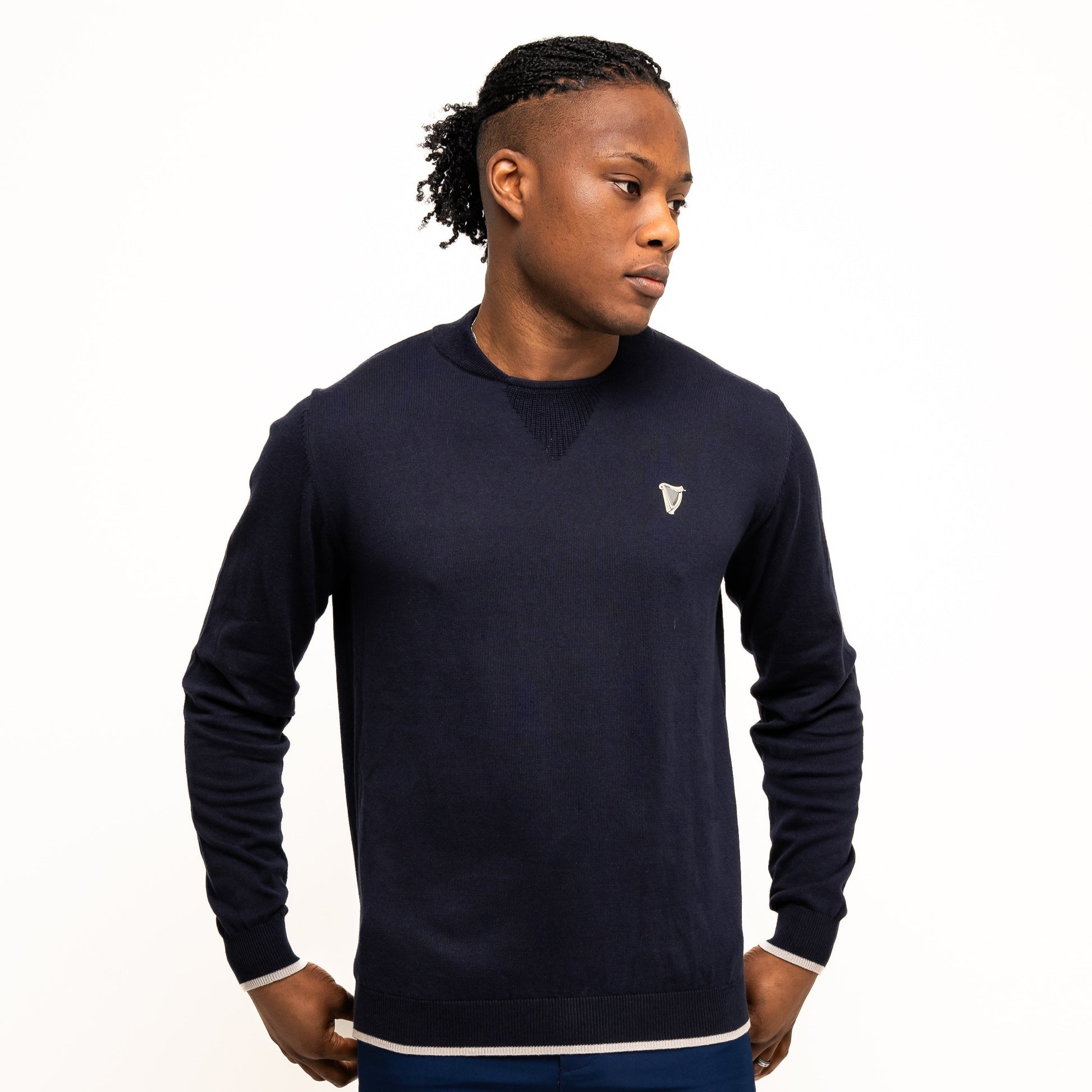 A person models the Guinness Performance Cotton Sweater - Navy from Guinness Webstore US with a small crest and navy shorts against a white background—ideal style for on or off the golf course.