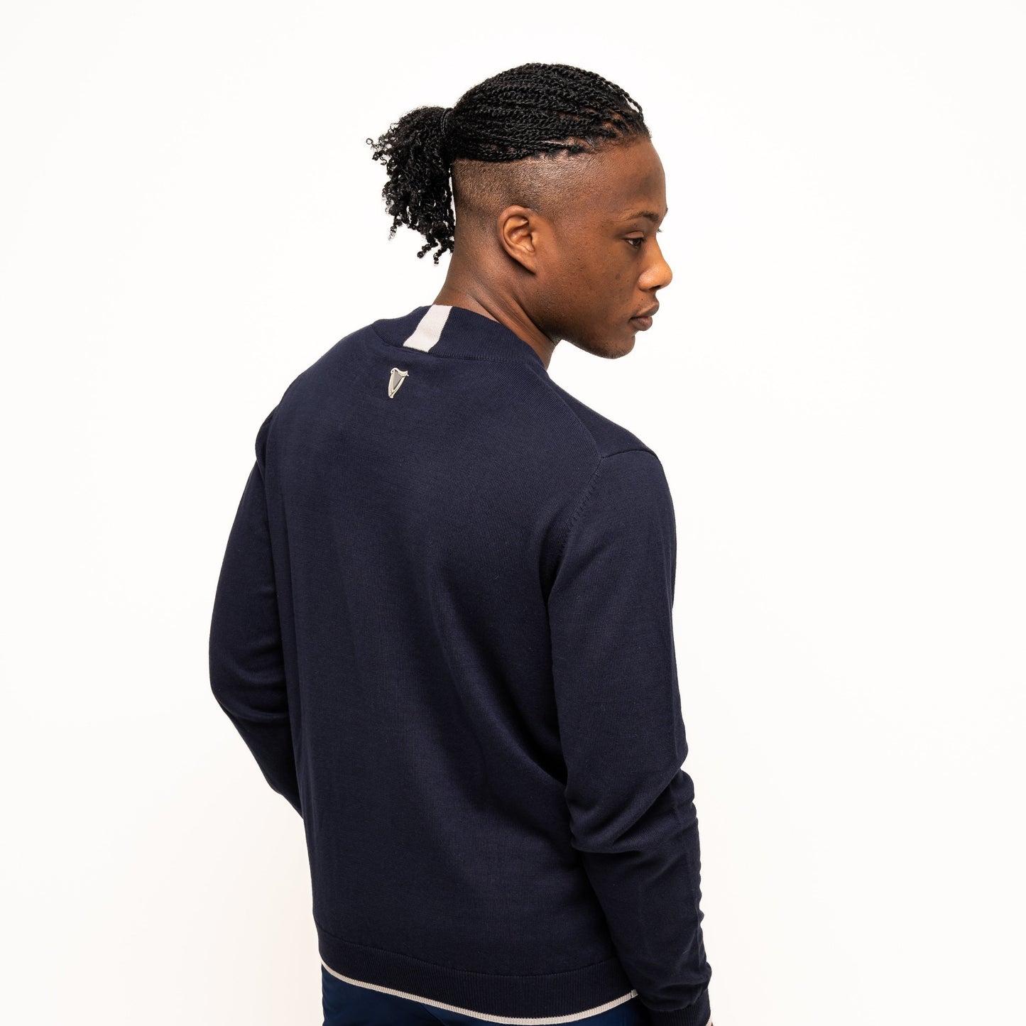 A person models the Guinness Performance Cotton Sweater - Navy from Guinness Webstore US, standing with their back turned and looking over their shoulder against a plain white background.