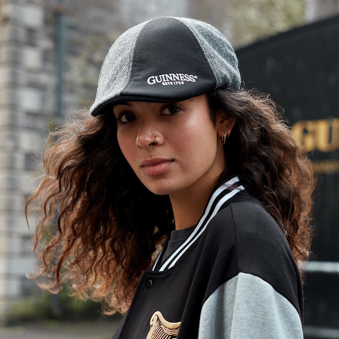 A young woman wearing a Guinness embroidered black and grey paneled Ivy cap.