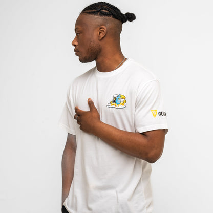 A man stands in profile wearing the Guinness Seb Curi Oversize Tee - White from Guinness Webstore US, featuring a small graphic and "GUINNESS" logo on the sleeve, created in collaboration with Sebastian Curi, against a plain white background.