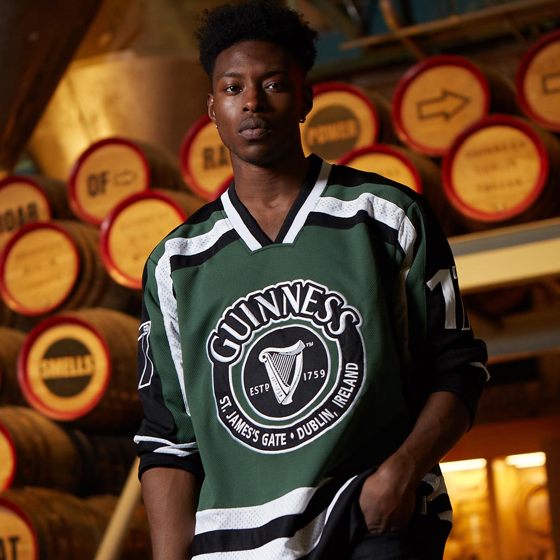 A young man wearing a Guinness Green & White Hockey Jersey made of polyester.