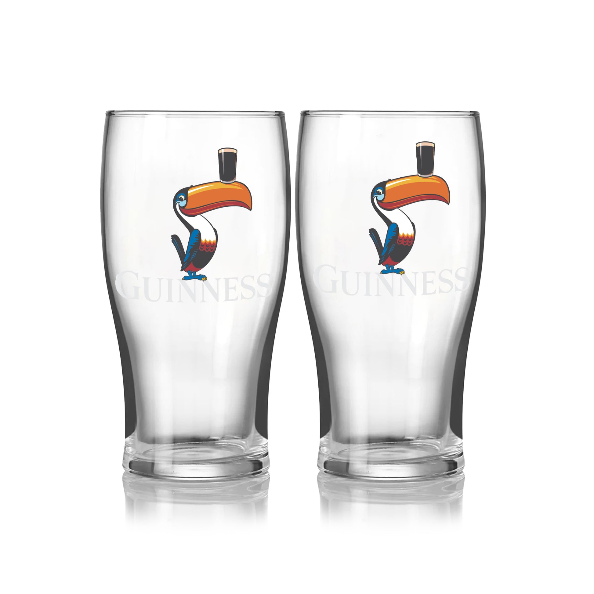 The Guinness Toucan Pint Glass Twin Pack features two clear pint glasses with classic Guinness branding and a colorful toucan illustration balancing a pint on its beak.