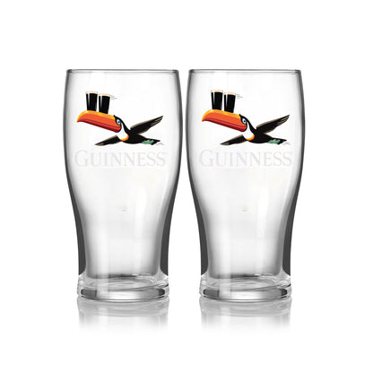 The Guinness Gilroy Flying Toucan Pint Glass - 2 Pack from Guinness Webstore US features two clear pint glasses with iconic branding and a flying toucan design, displayed side by side on a white background.